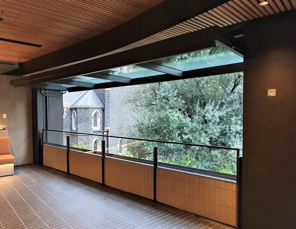 A large tilt window open and overlooking a park