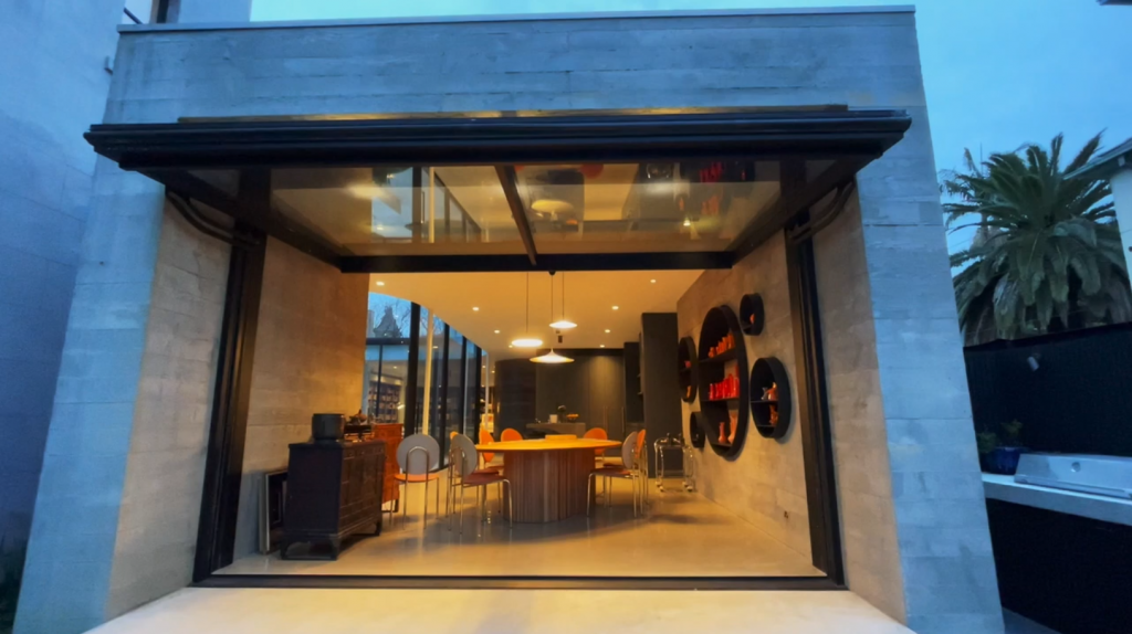 a glazed open wall opens to a family dinning room in the early evening