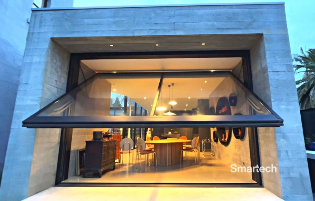 a beautiful concrete facade opens up to a family dinning room through an open glazed wall