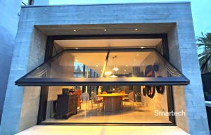 a beautiful concrete facade opens up to a family dinning room through an open glazed wall