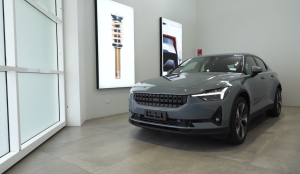 Polestar 2 car in white showroom with closed tilt door, two pictures on wall, and frosted privacy glass