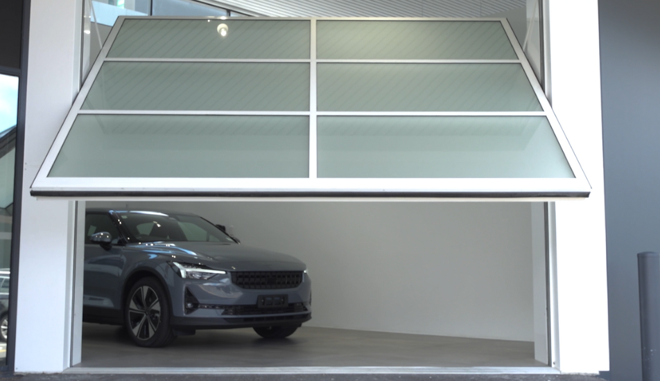 Polestar 2 car prepare to leave white showroom through tilt door opening