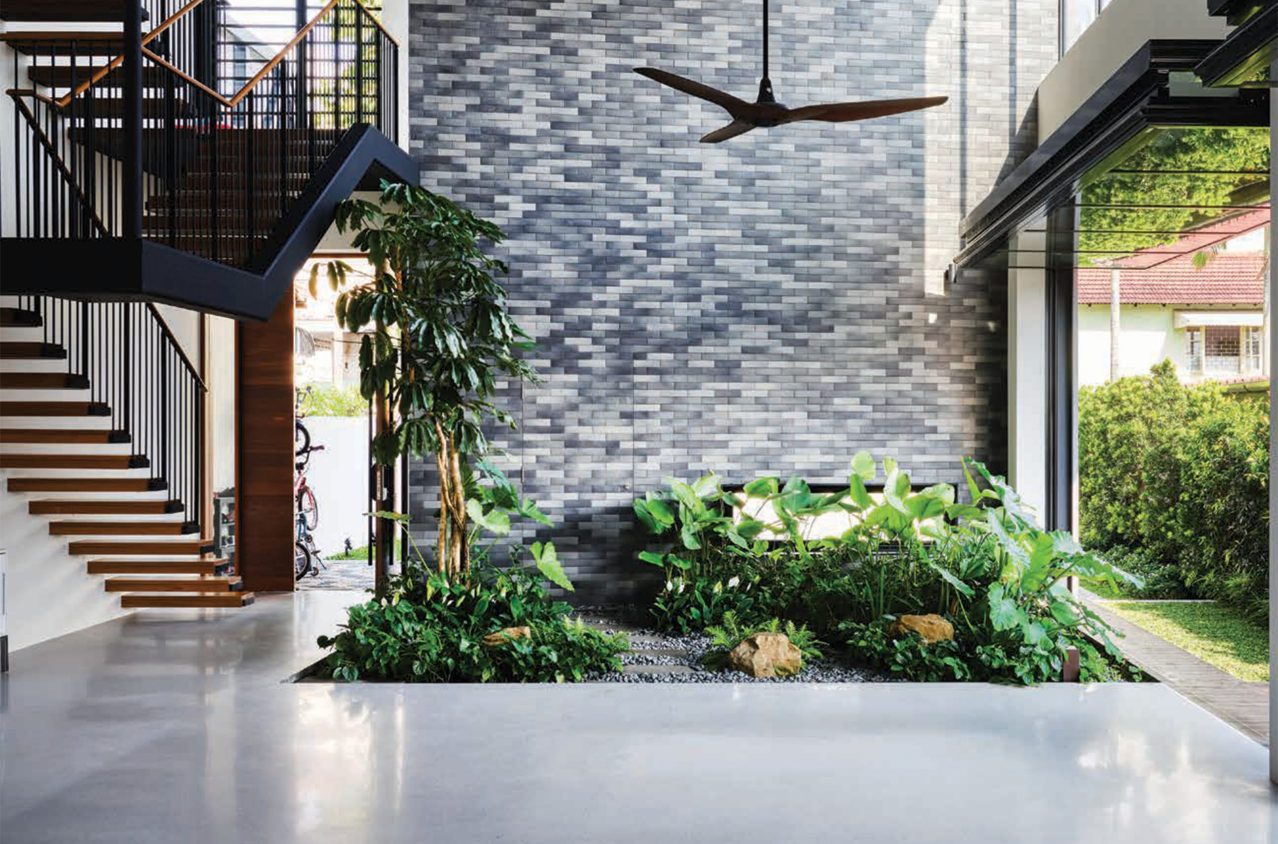 A beautiful two-story home in Singapore featuring multiple glazed folding doors with a small indoor garden